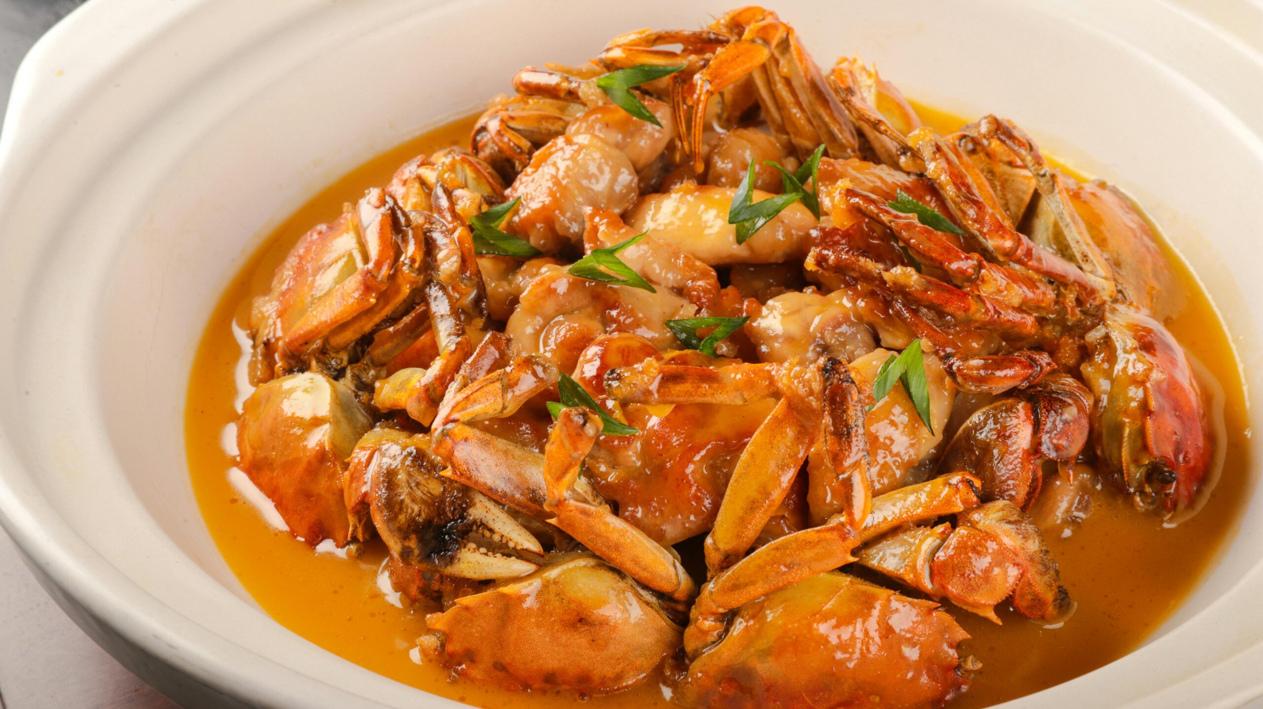 A savory dish of crabs in a rich, flavorful sauce garnished with fresh herbs.